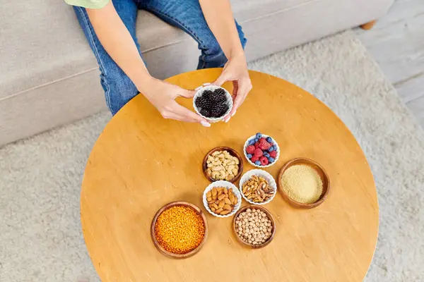 Cropped view of woman with fresh blackberries near set of vegetarian products on table at home — Stock Photo