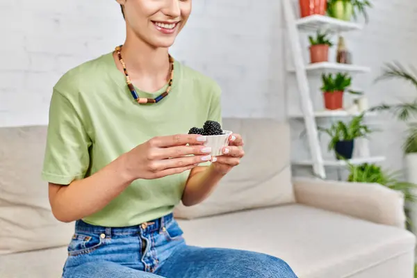 Vista recortada de mujer vegetariana sonriente con tazón de moras maduras, concepto de dietas a base de plantas - foto de stock