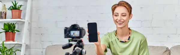 Donna vegetariana che tiene smartphone con schermo vuoto vicino alla fotocamera digitale durante il video blog, banner — Foto stock