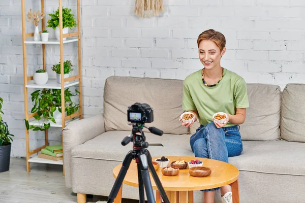 Happy vegetarian woman with nuts presenting set of plant-based ingredients during video blog at home — Stock Photo