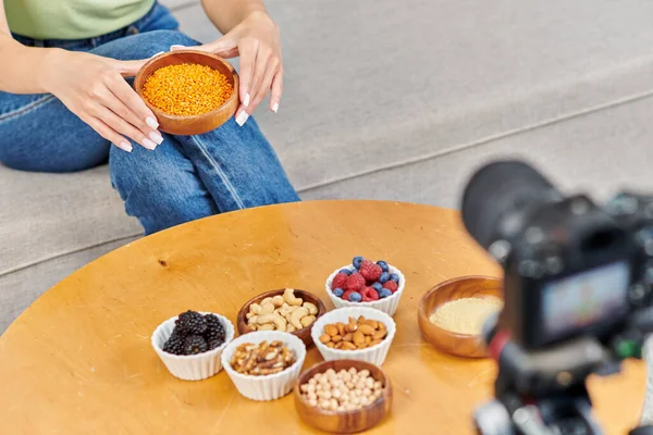 Mulher cortada com tigela de lentilhas perto da mesa com frutas frescas e nozes na frente da câmera digital — Fotografia de Stock