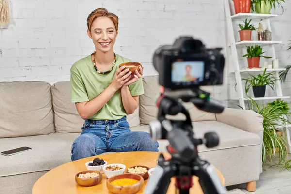 Video blogger vicino alla fotocamera digitale offuscata e set di alimenti a base vegetale in salotto, vegetarianismo — Foto stock
