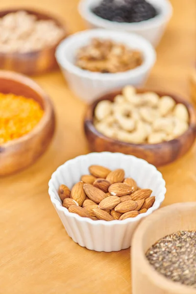 Bowl with delicious almonds near plant-based food on blurred background, vegetarian nutrition — Stock Photo
