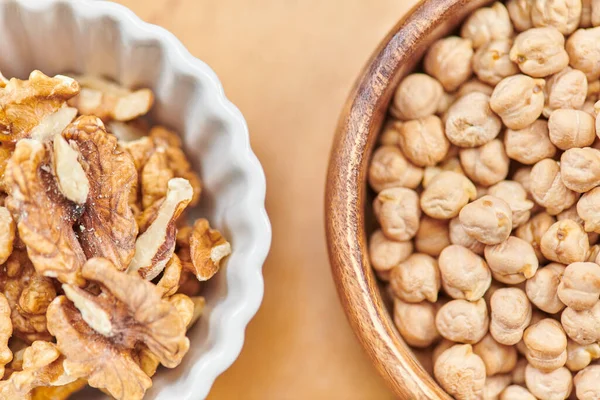 Top close up view of chickpeas and walnuts in wooden and ceramic bowls, plant-based diets concept — Stock Photo