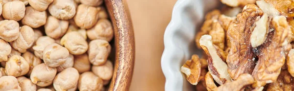 Вид сверху на высококалорийный горох и грецкие орехи в мисках, концепция диеты на растительной основе, баннер — стоковое фото