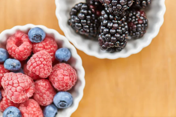 Close up of ripe blackberries and blueberries with raspberries in bowls, delicious vegetarian diet — Stock Photo