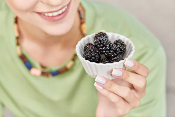 Cropped view of joyful woman with bowl of ripe blackberries, delicious vegetarian diet concept — Stock Photo