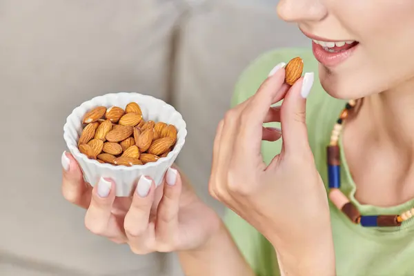 Partial view of young woman with white ceramic bowl of almonds, delicious vegetarian diet concept — Stock Photo