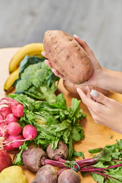 Mãos femininas com batata-doce acima do rabanete fresco e beterrabas perto de frutas, dieta vegetariana saudável — Fotografia de Stock