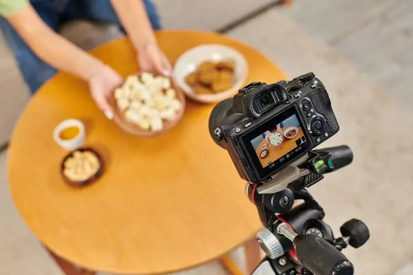 Focus on digital camera near women with plate of vegetarian tofu cheese near vegetarian meal — Stock Photo