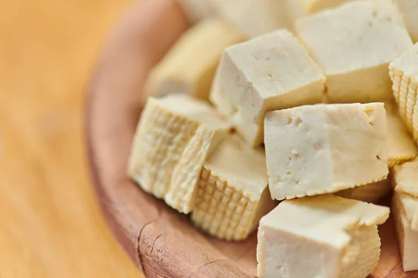 Close up view of diced delicious tofu cheese on wooden plate, delicious vegetarian diet concept — Stock Photo