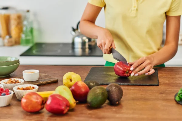 Mulher cortada maçã de corte perto de frutas frescas e vários ingredientes de origem vegetal, dieta à base de plantas — Fotografia de Stock