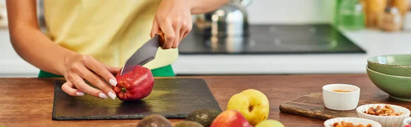 Vista ritagliata della donna che taglia mela vicino a frutta matura e vari ingredienti vegetariani, banner — Foto stock