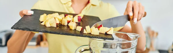 Vue partielle de la femme végétarienne ajoutant pomme hachée mûre dans un mélangeur électrique, bannière horizontale — Photo de stock