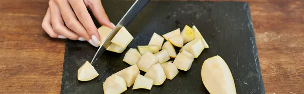 Vue partielle de la femme végétarienne avec couteau coupant poire fraîche mûre sur planche à découper, bannière — Photo de stock
