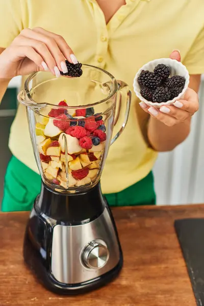 Abgeschnittene Ansicht einer Vegetarierin, die Brombeeren in einen elektrischen Mixer mit köstlichen Früchten gibt — Stockfoto