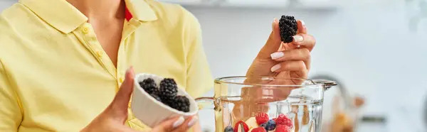 Cropped view of vegetarian woman with ripe blackberries near blender with chopped fruits, banner — Stock Photo