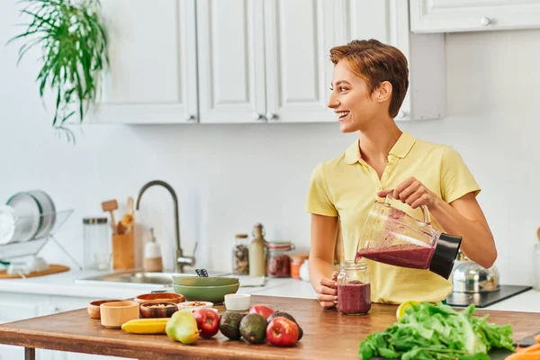 Donna allegra versando frullato vegetariano da frullatore in vaso muratore, concetto di dieta a base vegetale — Foto stock