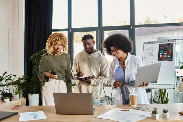 Alegre equipe de amigos afro-americanos trabalhando juntos e olhando para laptop, conceito de negócio — Fotografia de Stock