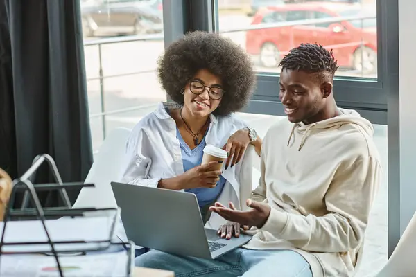 Dois amigos alegres em roupas casuais com xícara de café em mãos olhando para laptop, conceito de negócio — Fotografia de Stock