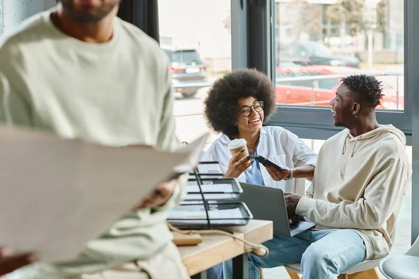 Vista recortada del hombre afroamericano con sus amigos trabajando en el telón de fondo, concepto de coworking - foto de stock