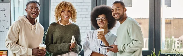 Afrikanisch-amerikanische Freunde mit Kaffeetassen, die fröhlich in die Kamera lächeln, Arbeitsprozess, Banner — Stockfoto