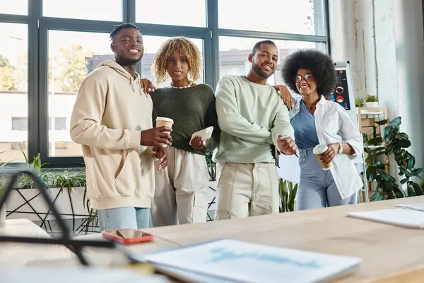 Junge afrikanisch-amerikanische Freunde posieren mit Handy- und Kaffeetassen und lächeln vor der Kamera, Coworking — Stockfoto