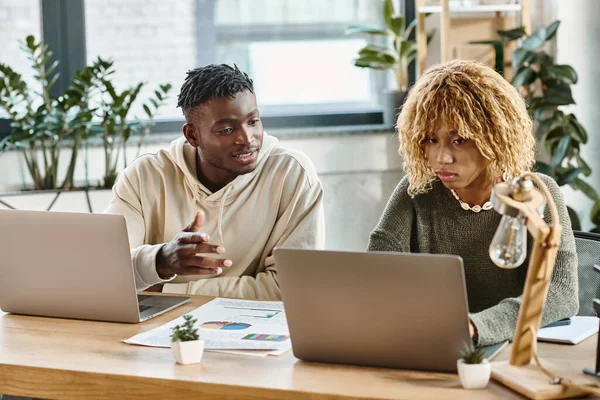 Zwei gut aussehende Freunde, die an Laptops arbeiten und über ihr Coworking-Konzept diskutieren — Stockfoto