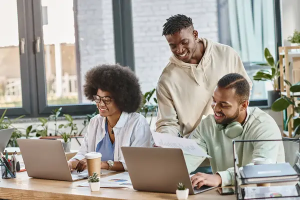 Drei glückliche junge afrikanisch-amerikanische Freunde arbeiten munter an ihrem Projekt, Geschäftskonzept — Stockfoto