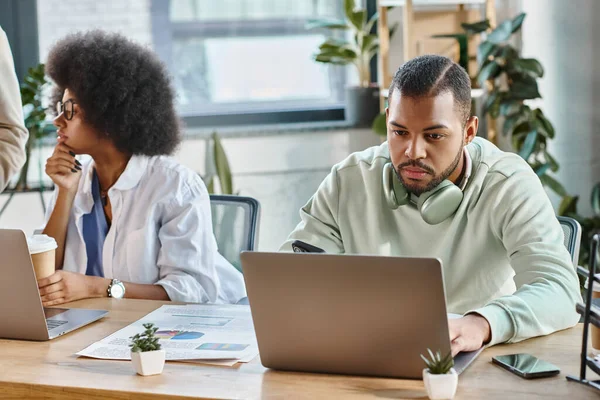Handsome young man working with laptop while his female friend looking away, business concept — Stock Photo