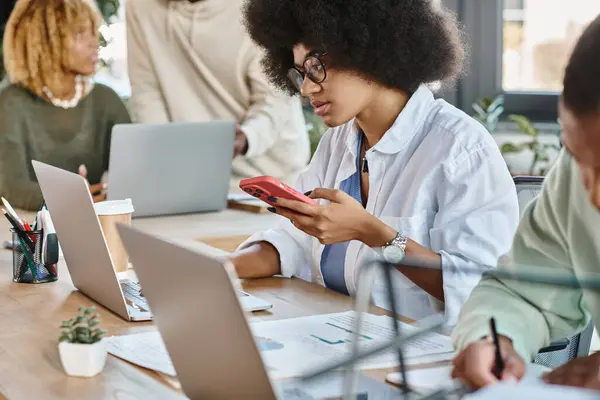 Attractive african american woman working on laptop with cropped view of her friends, coworking — Stock Photo