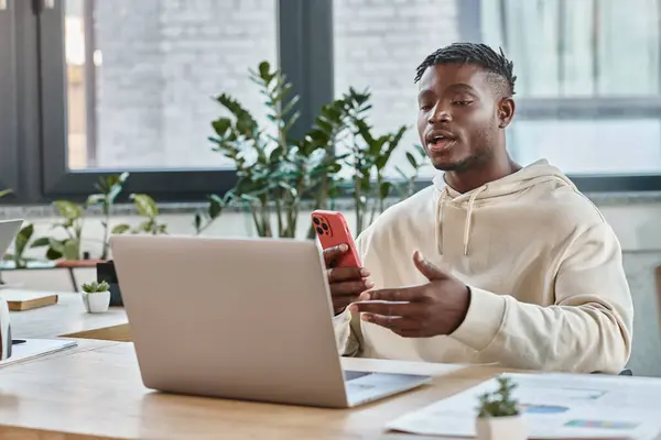 Homem americano africano elegante falando com alguém por laptop e gesticulando ativamente, conceito de trabalho — Fotografia de Stock