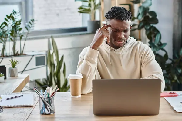 Konzentrierter und verwirrter Mann mit Hand in der Nähe seiner Schläfe, der auf seinen Laptop blickt, Arbeitsprozess — Stockfoto
