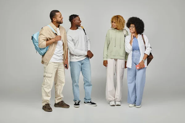 Cheerful good looking group of students posing with backpacks on gray background, studying concept — Stock Photo