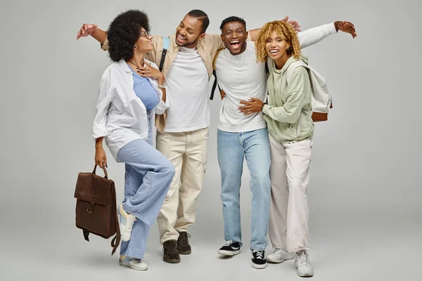 Good looking smiley friends posing actively and hugging on light gray backdrop, student lifestyle — Stock Photo