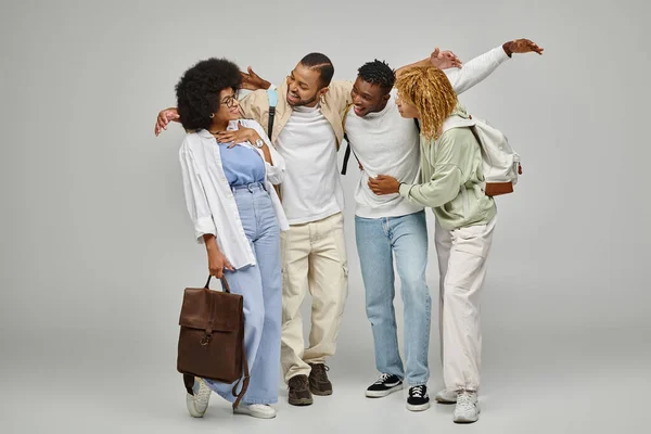 Joyous african american friends smiling at each other cheerfully on gray background, students — Stock Photo