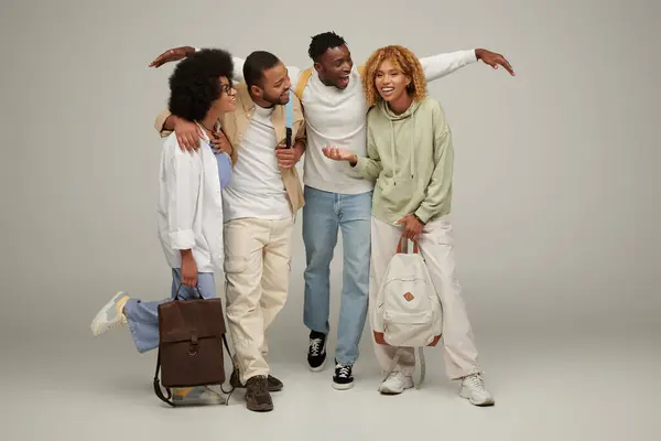 Young stylish friends in casual wear with backpacks talking lively and smiling cheerfully, students — Stock Photo