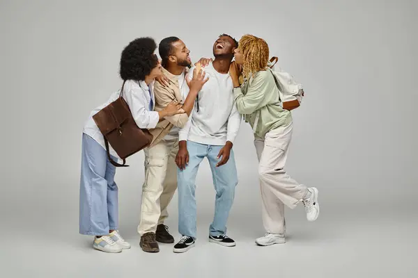 Cheerful caring group of friends hugging and laughing together on gray backdrop, studying concept — Stock Photo