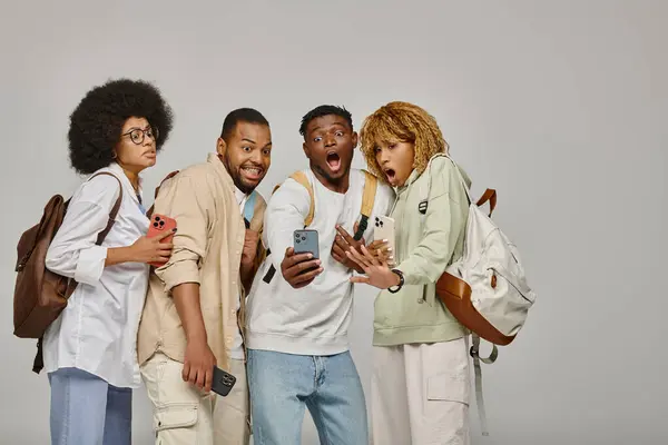 Astonished african american friends looking shockingly at smartphone smiling cheerfully, students — Stock Photo