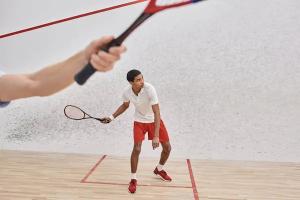 African american man in sportswear playing with friend inside of squash court, blurred foreground — Stock Photo