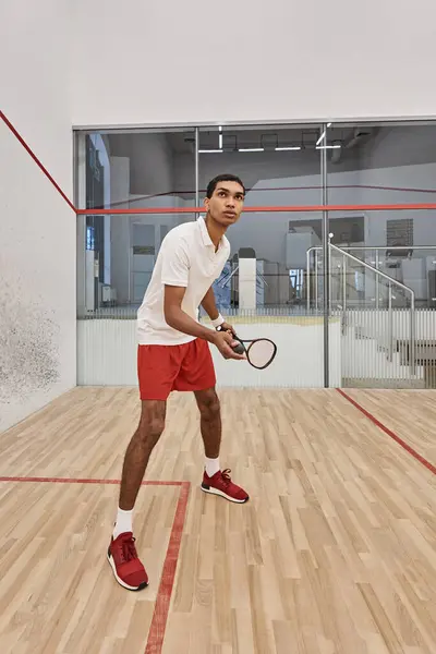Tiro vertical de desportista afro-americano segurando bola de squash e raquete enquanto joga jogo — Fotografia de Stock