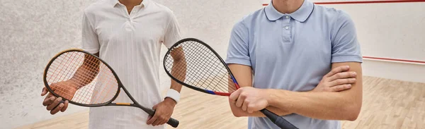 Cortado interracial masculino amigo de pé junto com squash raquetes no tribunal, banner — Fotografia de Stock