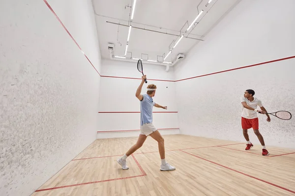 Multicultural players in sportswear playing squash together inside of court, active lifestyle — Stock Photo