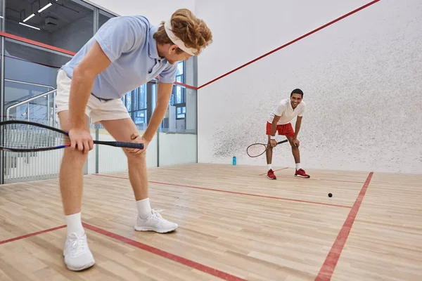 Tired interracial friends in sportswear breathing heavily after playing squash in court, motivation — Stock Photo
