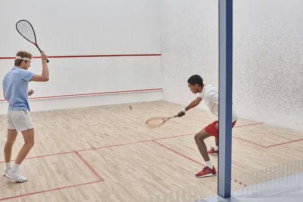 Amis multiculturels en vêtements de sport jouer ensemble à l'intérieur du court de squash, la motivation et le sport — Photo de stock