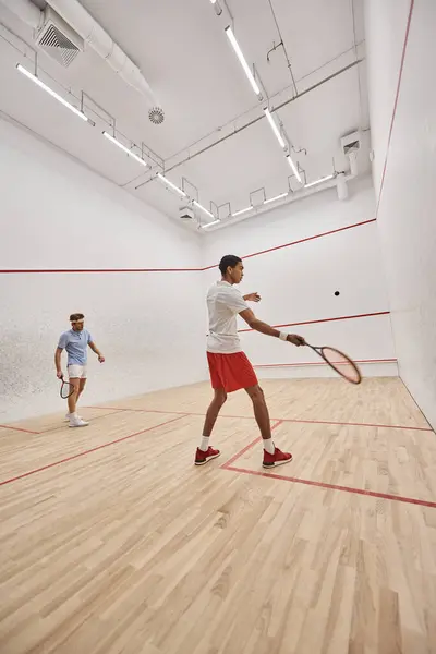 Jeunes sportifs interraciaux jouant au squash ensemble à l'intérieur du court intérieur, la motivation et le sport — Photo de stock