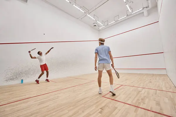 Atlético e diversos homens em sportswear jogar squash juntos dentro da corte, motivação — Fotografia de Stock