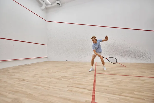 Jovem e ativo ruiva homem em sportswear jogar squash dentro da corte, desafio e motivação — Fotografia de Stock