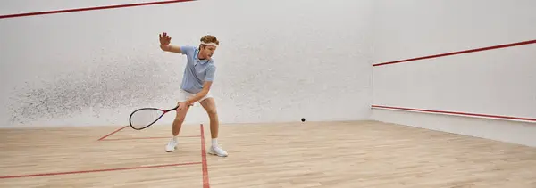 Young and active redhead man in sportswear playing squash inside of court, challenge banner — Stock Photo