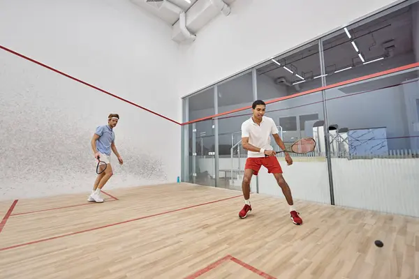 Junge multiethnische Spieler in Sportbekleidung beim Squash auf dem Platz, Anstrengung und Motivation — Stockfoto
